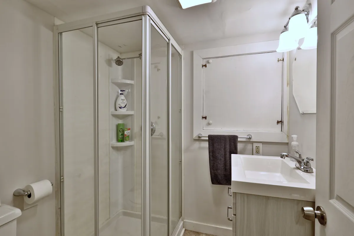 A modern and tidy bathroom featuring a shower cubicle, sink, and mirror, all arranged with a sense of order and cleanliness. The space feels refreshing and functional, supporting smooth daily routines.