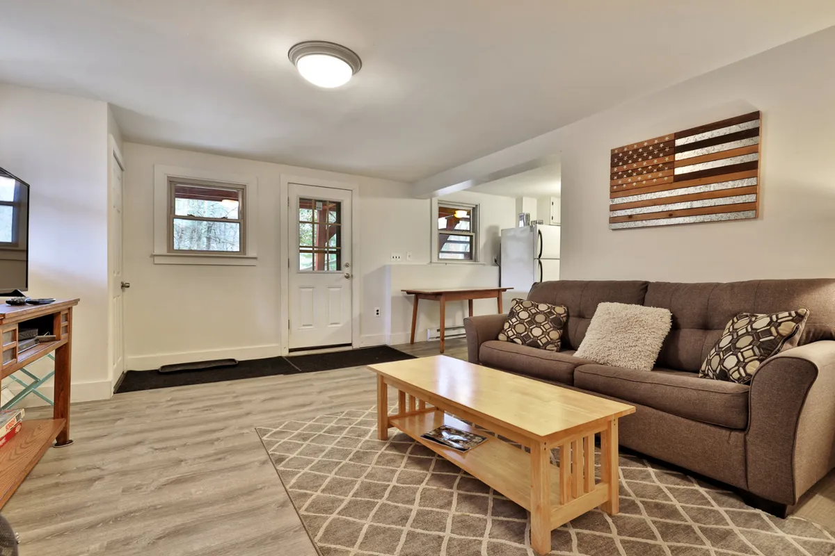 A cozy living space featuring a sofa adorned with decorative pillows, a coffee table perfect for gathering around, and warm Americana-themed wall art. The setting feels welcoming, ideal for group conversations or relaxing after an event.