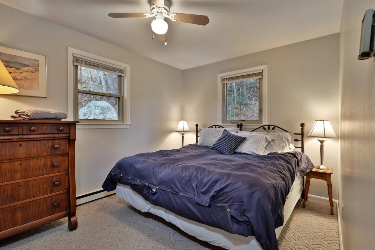 A serene bedroom with a plush bed, matching dresser and nightstands, softly lit by lamps, and windows that let in gentle natural light. The inviting atmosphere suggests peaceful sleep and a space tailored for relaxation and privacy.