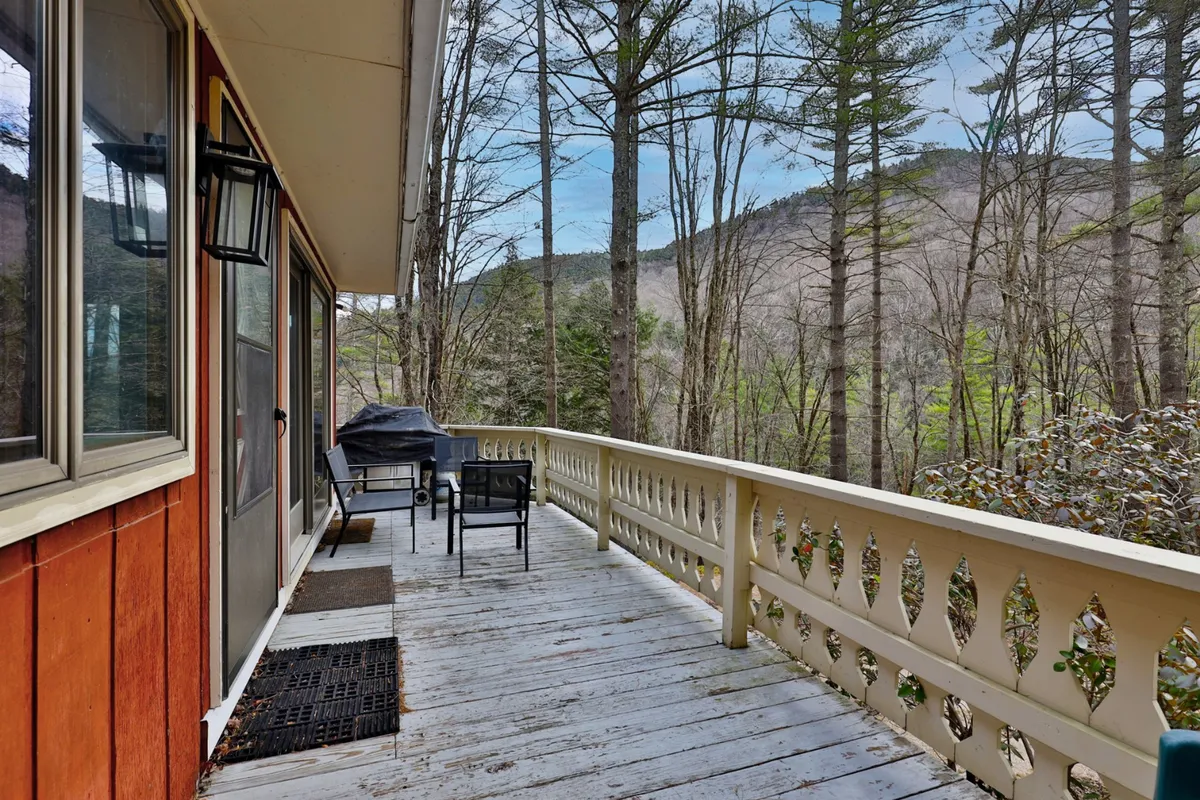 A peaceful deck with a railing, offering a clear view of the surrounding mountains and trees. Comfortable outdoor seating is visible, perfect for lounging at any time of day. The vantage point provides a sense of openness and connection to nature, ideal for unwinding after adventures.